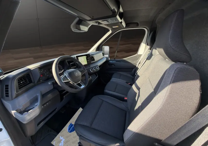 Vue intérieure côté conducteur du Renault Master blanc 2026, montrant le tableau de bord et les sièges avant gris.
