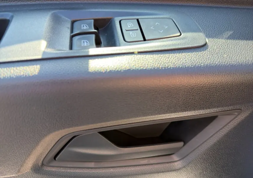 Gros plan sur la commande des vitres et réglage des rétroviseurs côté conducteur dans un Renault Master blanc.