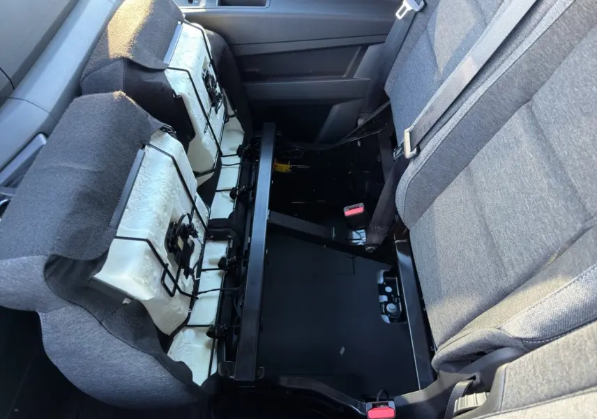 Vue intérieure côté droit du siège arrière relevé du Renault Master blanc, montrant la structure métallique et les fixations du siège.