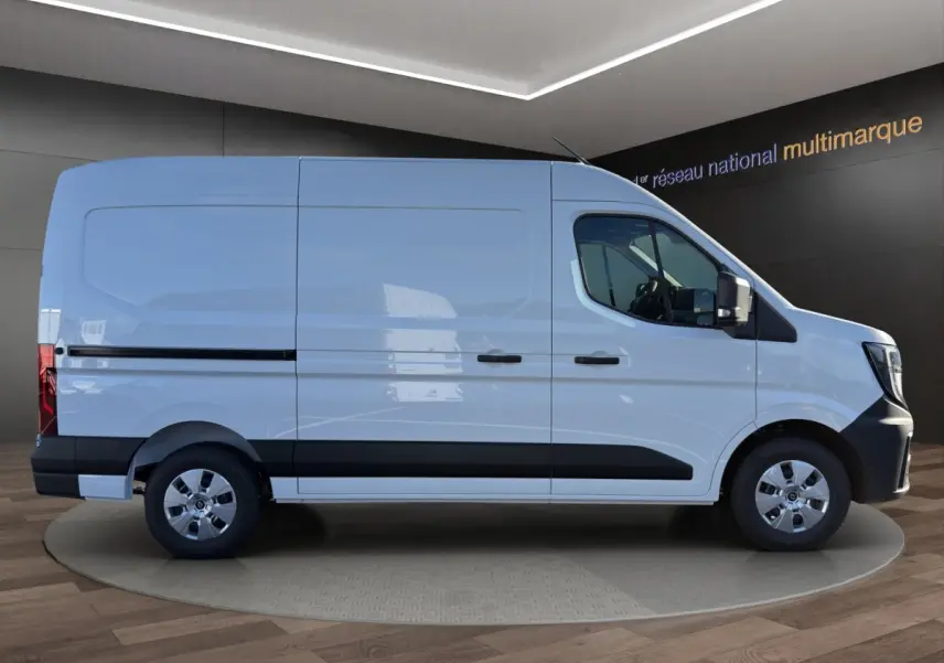 Profil droit d’un utilitaire Renault Master blanc avec bande noire et jantes argentées, en intérieur showroom.