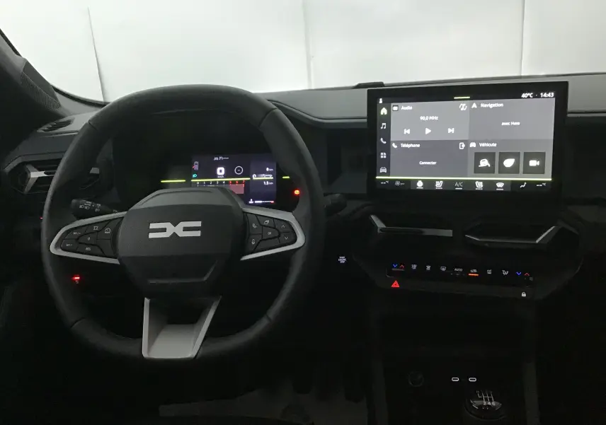 Vue intérieure du tableau de bord du Dacia Bigster 2025, avec volant multifonction, écran tactile central et levier de vitesses manuel.
