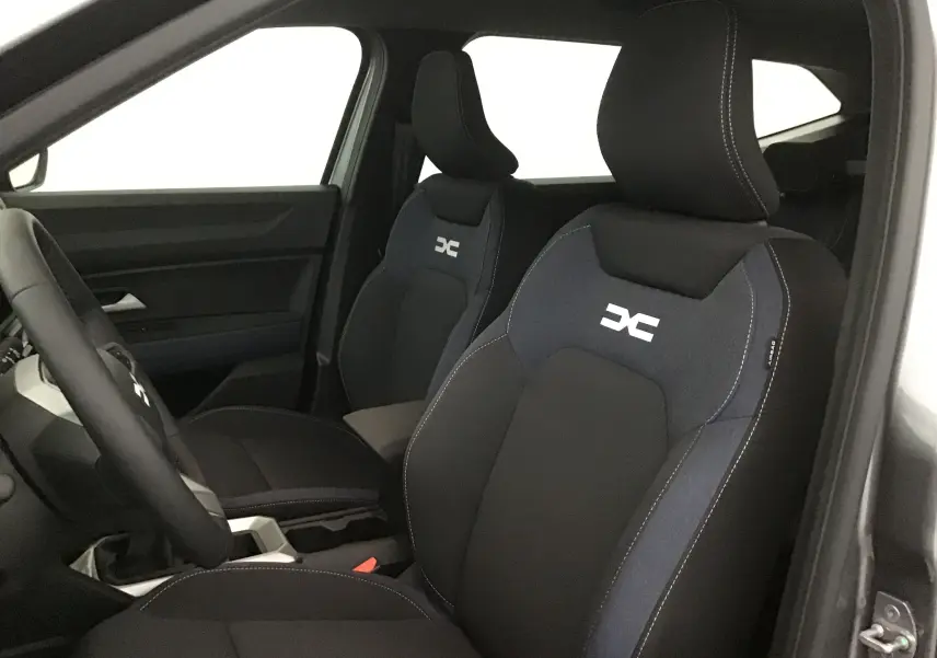 Vue intérieure côté gauche du Dacia Bigster 2025, sièges noirs avec logo blanc DC et surpiqûres contrastantes.