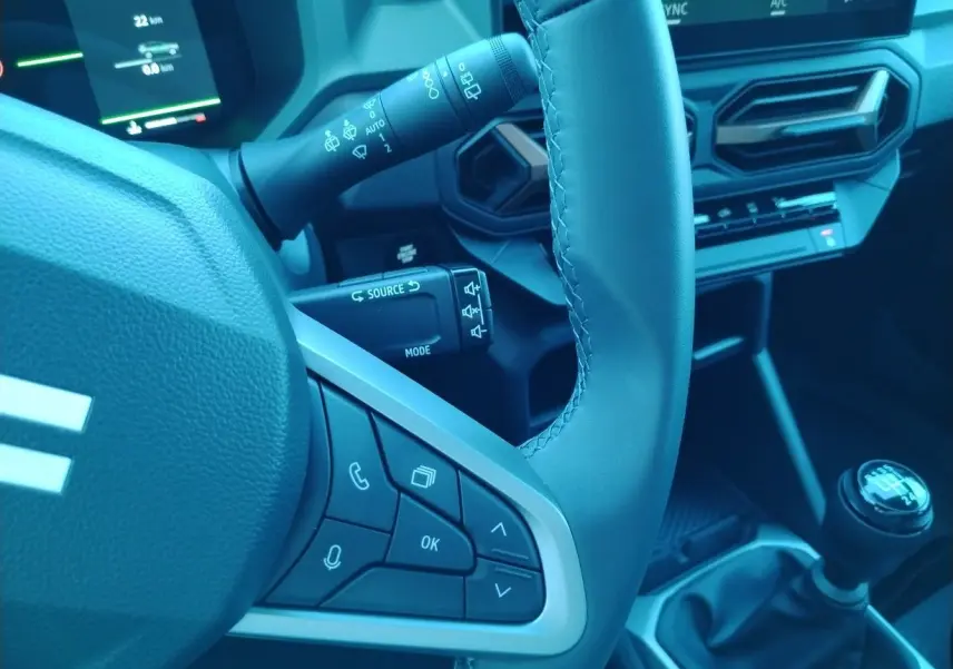 Gros plan sur le volant noir et la commande de boîte manuelle du Dacia Bigster 2025, avec tableau de bord digital en arrière-plan.