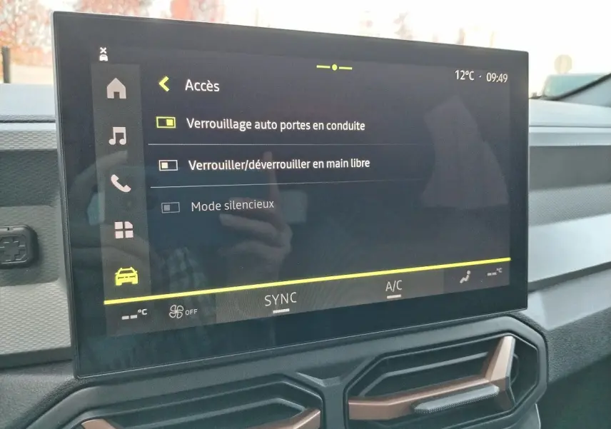 Écran tactile central affichant les réglages d'accès du DACIA BIGSTER 2025, intérieur moderne avec aérateurs hexagonaux.