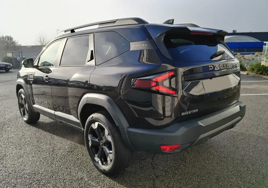 Vue 3/4 arrière droite du SUV noir Dacia Bigster 2025 avec jantes noires et feux arrière en forme de flèche.