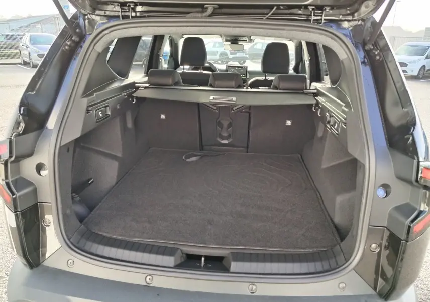 Vue arrière du coffre ouvert d'un Dacia Bigster noir 2025, montrant l'espace de chargement et la banquette arrière.