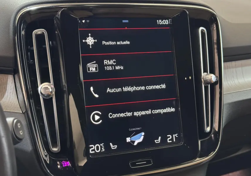 Écran tactile central du tableau de bord du Volvo XC40 noir, affichant la radio et la climatisation en intérieur.