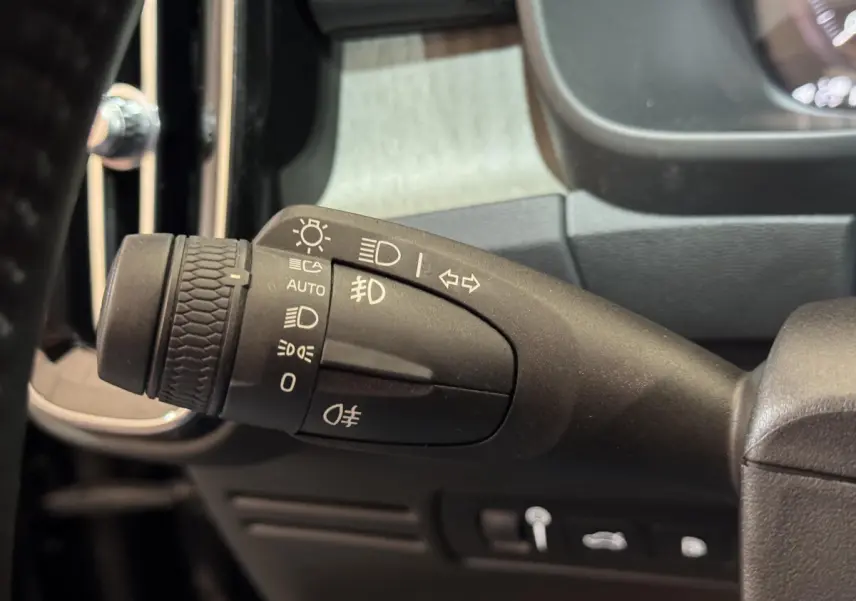 Gros plan sur la commande des phares et clignotants à gauche du volant dans un Volvo XC40 noir de 2021.
