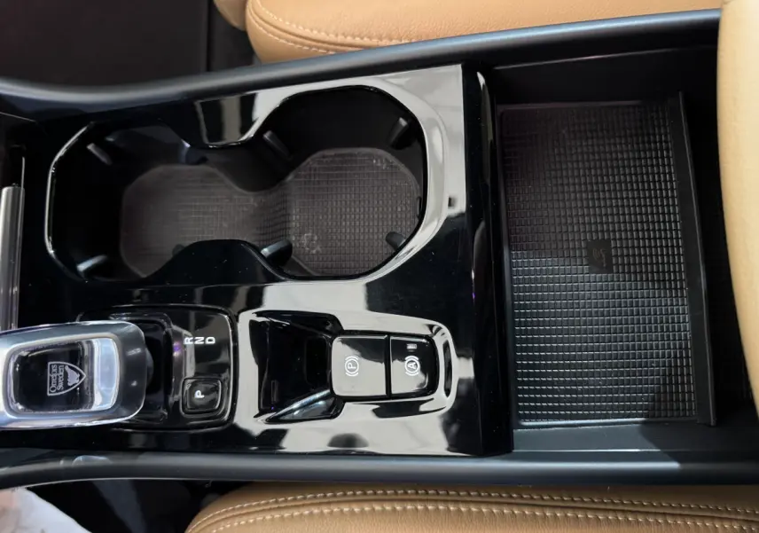 Gros plan sur la console centrale noire brillante du Volvo XC40 Recharge T5 avec sellerie cuir beige visible.