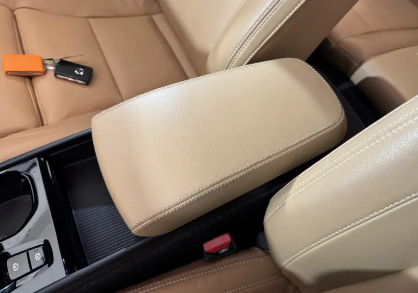 Accoudoir central beige en cuir vu de dessus dans l'habitacle du Volvo XC40 Recharge T5 noir avec clés posées sur le siège.