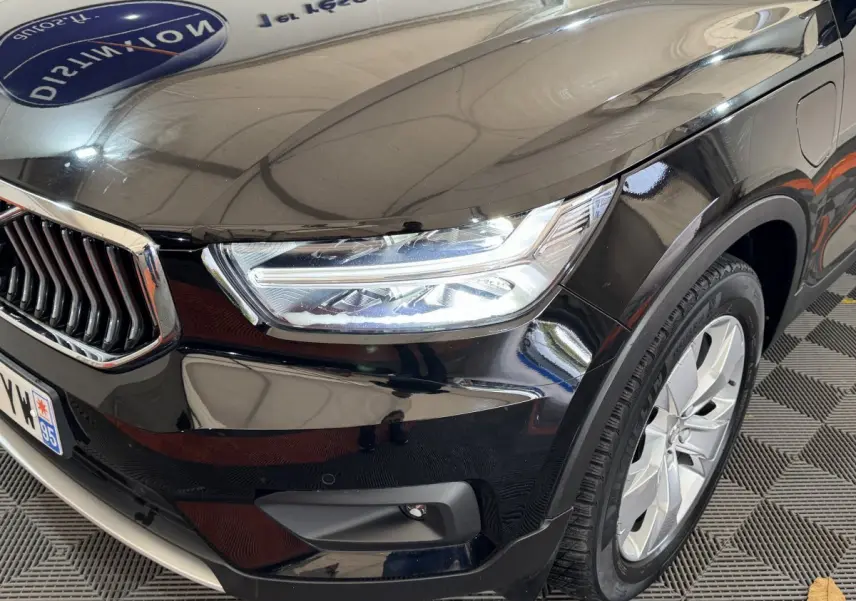 Gros plan sur l'avant droit noir brillant du Volvo XC40 Recharge T5 avec phares LED et jante alu visible.