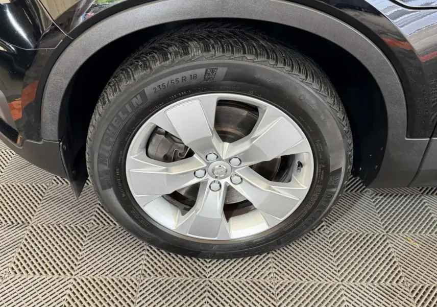 Gros plan sur la roue avant gauche avec jante argentée du Volvo XC40 noir Recharge T5 262 DCT7 Inscription 2021.