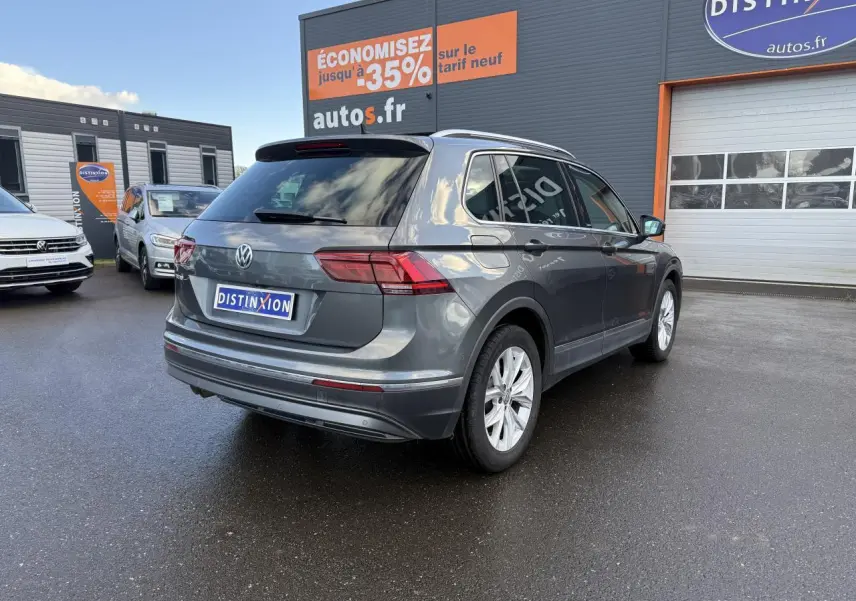 Volkswagen Tiguan gris Indium métallisé vu en 3/4 arrière droit sur parking devant un garage autos.fr