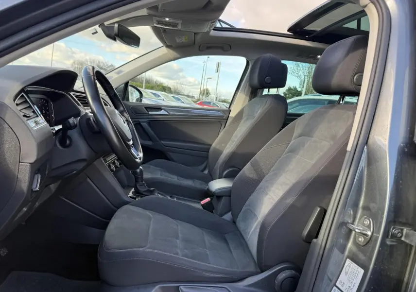 Vue intérieure côté conducteur du Volkswagen Tiguan gris Indium, sièges sport et toit ouvrant panoramique visibles