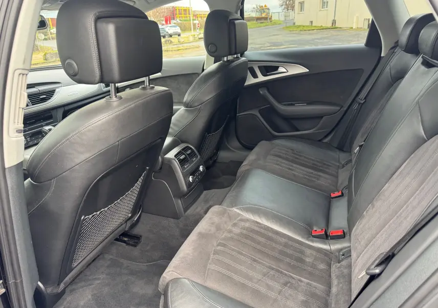 Vue intérieure arrière droite de l’Audi A6 Avant 2015 avec sièges cuir et alcantara noirs et console centrale avec aérateurs.