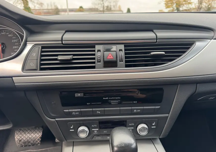 Vue rapprochée du tableau de bord noir de l'Audi A6 Avant 2015, mettant en valeur la console centrale et les aérateurs.