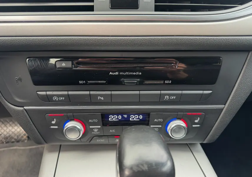 Vue rapprochée du tableau de bord de l'Audi A6 Avant 2015, montrant la console centrale avec commandes climatisation et multimédia.