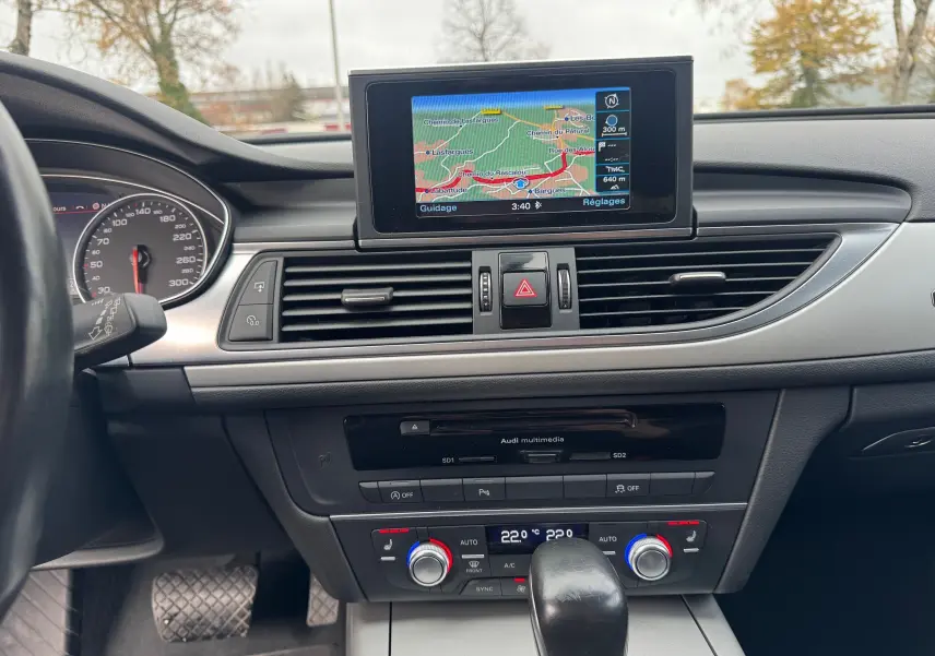Vue intérieure centrée sur le tableau de bord de l'Audi A6 Avant 2015, avec écran GPS et commandes climatisation visibles.