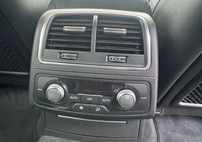 Vue rapprochée de la console de climatisation arrière noire de l’Audi A6 Avant 2015 avec commandes rotatives et aérateurs.