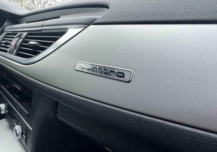 Détail intérieur du tableau de bord gris et noir de l’Audi A6 Avant 2015 avec logo quattro visible.