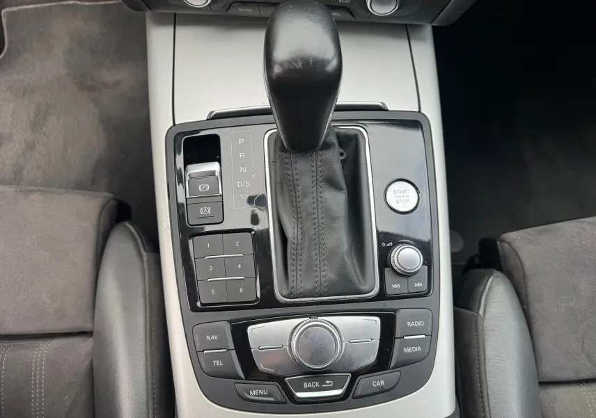 Vue plongeante sur la console centrale de l'Audi A6 Avant noire, mettant en valeur le levier de vitesse automatique et les commandes multimédia.