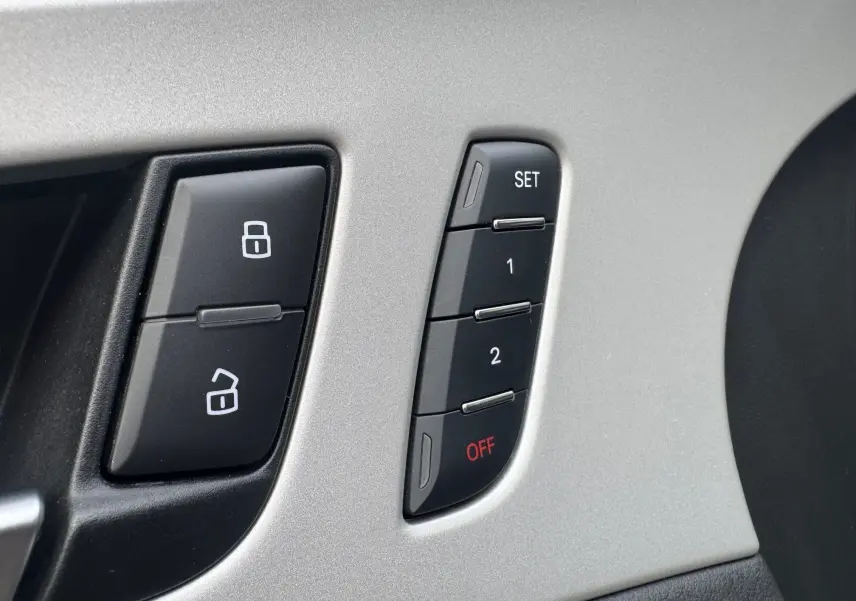 Gros plan sur les boutons de réglage mémoire des sièges et verrouillage des portes, intérieur gris et noir.