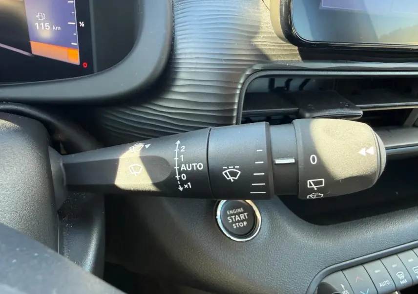 Gros plan sur la commande d’essuie-glace du Jeep Avenger blanc 2025, avec bouton démarrage et tableau de bord partiel.