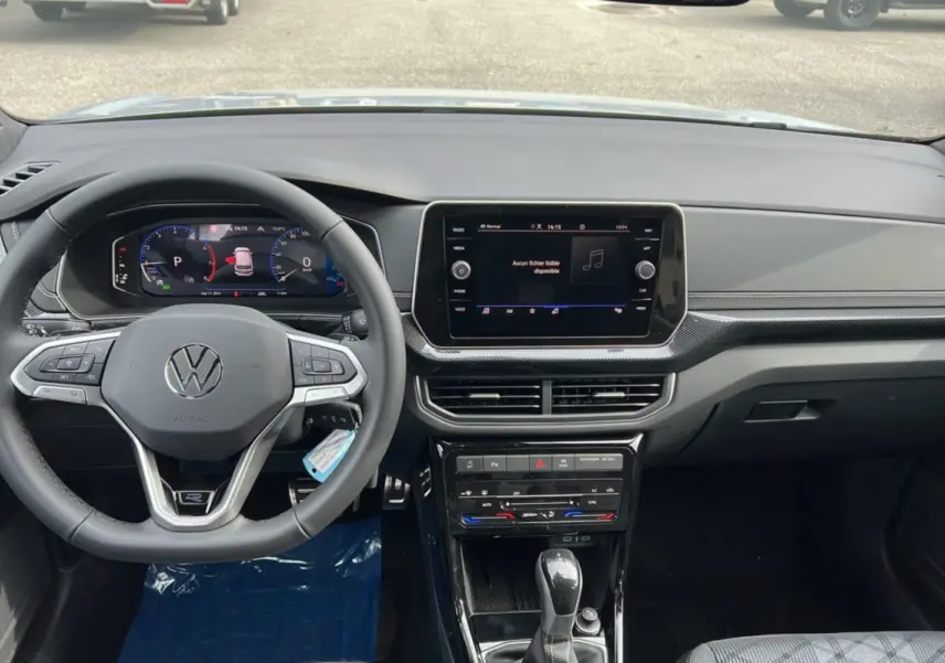 Vue intérieure du tableau de bord du Volkswagen T-Cross gris argent, avec volant multifonctions et écran tactile central.