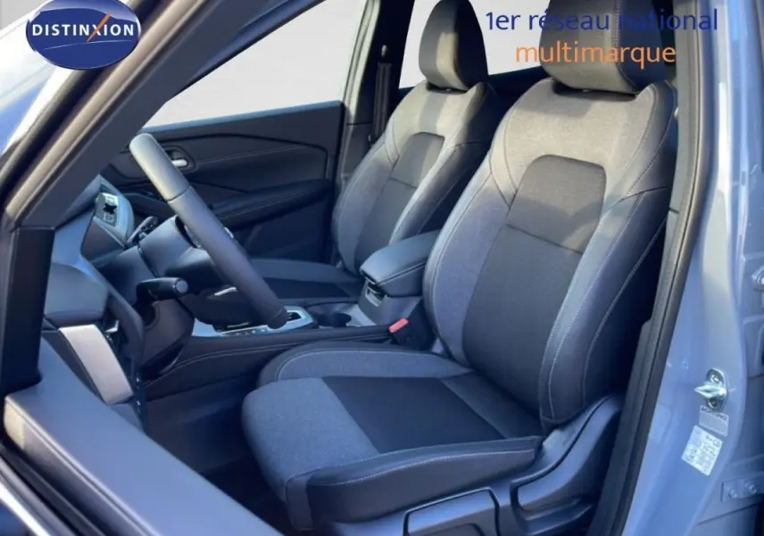 Vue intérieure côté conducteur du Nissan Qashqai gris 2025, montrant les sièges avant en tissu bi-ton et le volant.