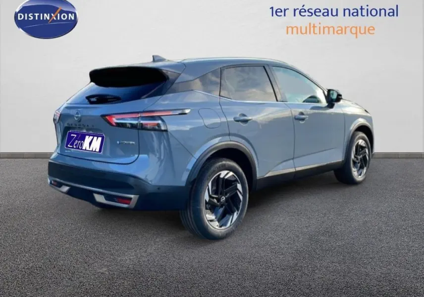 Nissan Qashqai gris 3/4 arrière droit, jantes aluminium et feux arrière effilés visibles sur fond neutre.