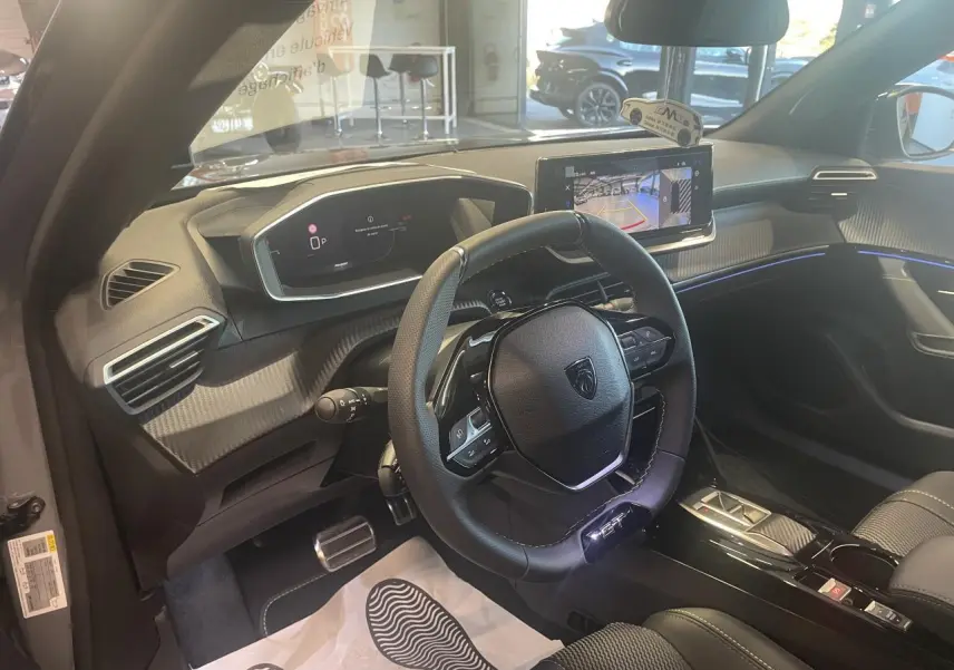 Vue intérieure côté conducteur du Peugeot 2008 gris, volant compact cuir et écran tactile avec caméra de recul affichée.