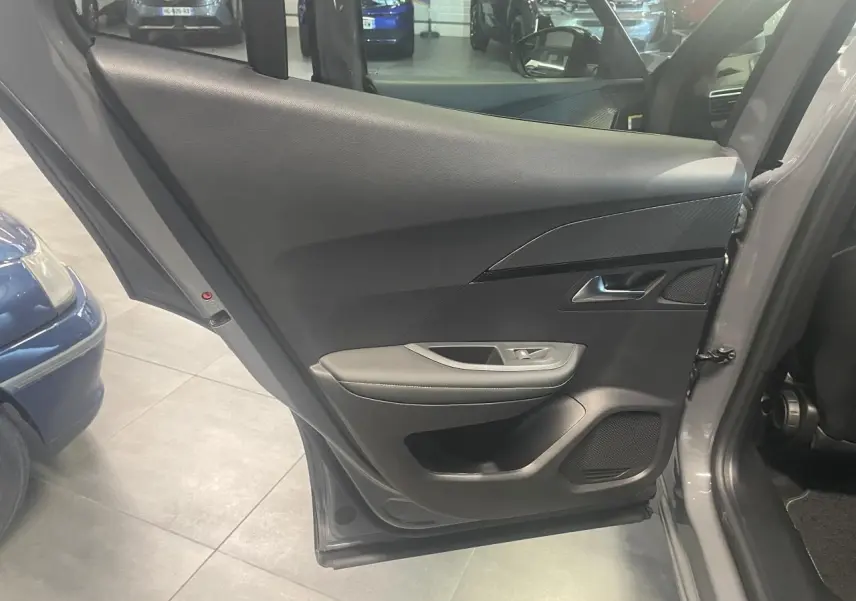 Porte arrière gauche ouverte du Peugeot 2008 gris, montrant le panneau intérieur noir avec accoudoir et haut-parleur intégré.