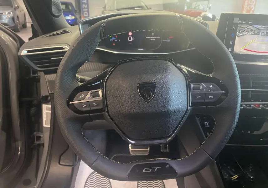 Vue intérieure centrée sur le volant cuir noir GT de la Peugeot 2008 1.2i Hybrid avec tableau de bord numérique.