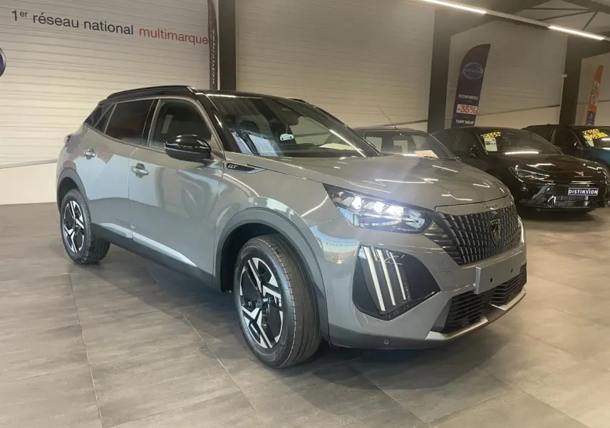 Peugeot 2008 gris en 3/4 avant droit, avec calandre noire et feux LED distinctifs allumés.