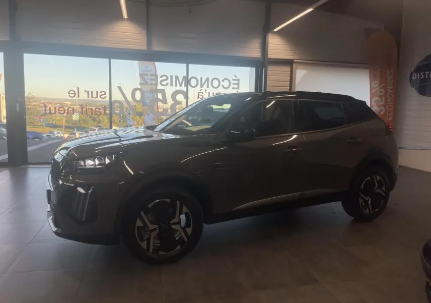 Peugeot 2008 gris en 3/4 avant droit, avec jantes noires et toit contrasté noir en intérieur showroom.