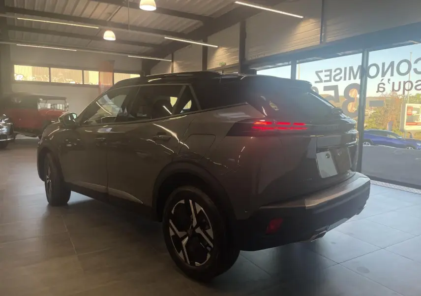 Peugeot 2008 gris en 3/4 arrière droit, avec feux arrière LED allumés et jantes au design moderne.