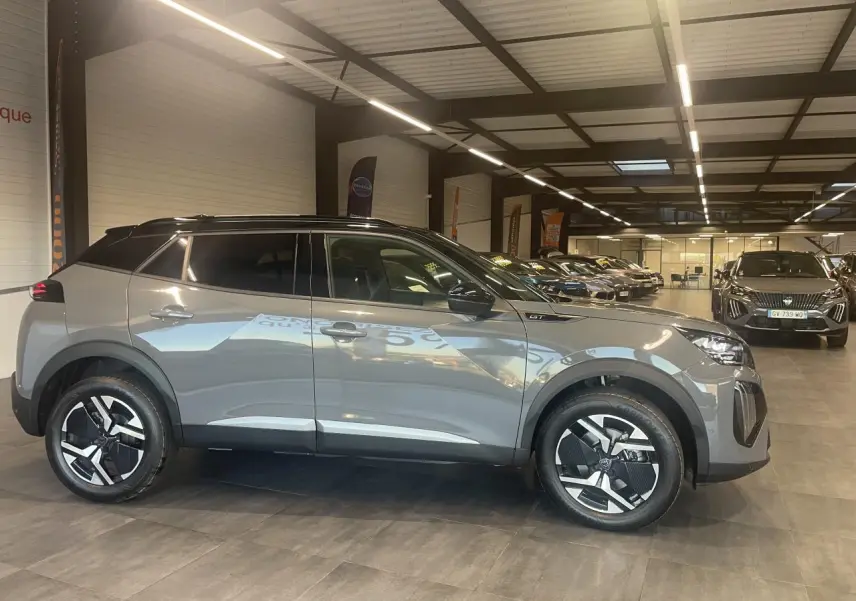 Peugeot 2008 gris métallisé vue de profil côté gauche en intérieur avec toit noir et jantes distinctives.