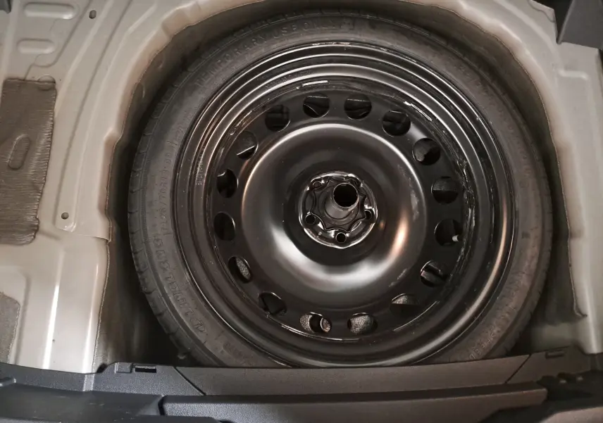 Gros plan sur la roue de secours galette noire dans le coffre du Volkswagen T-Cross Gris Ascot 2024.