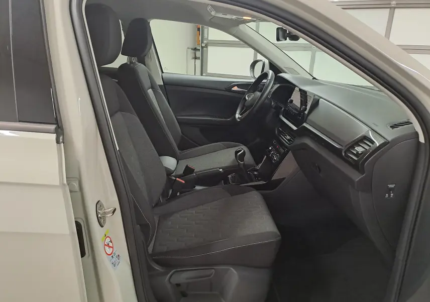 Vue intérieure côté conducteur du Volkswagen T-Cross 2024, sièges tissu gris et tableau de bord moderne.