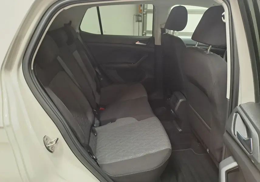 Vue intérieure arrière droite du Volkswagen T-Cross 2024 gris Ascot, montrant les sièges arrière en tissu bicolore.