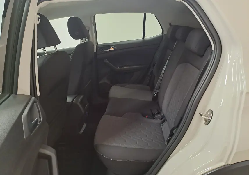 Vue intérieure arrière droite du Volkswagen T-Cross 2024, sièges tissu gris foncé et portière blanche ouverte.