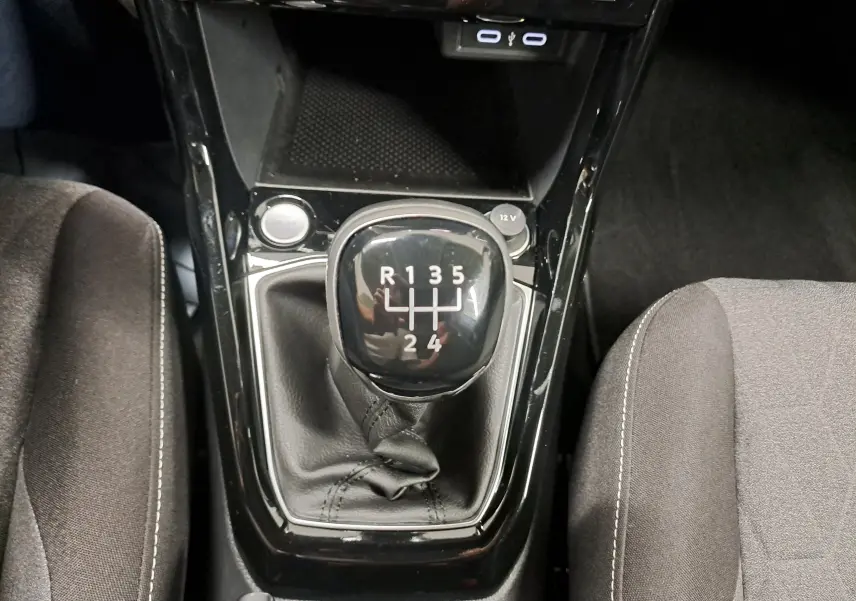Gros plan sur le levier de vitesses manuel du Volkswagen T-Cross 2024, entouré de sièges en tissu gris.