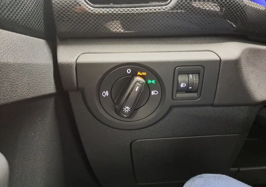Gros plan sur la commande des phares du Volkswagen T-Cross 2024, avec réglage rotatif et finition noire texturée.