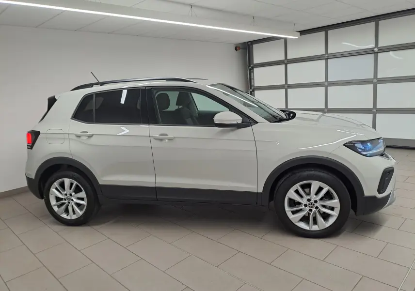 Vue de profil droit du Volkswagen T-Cross 2024 en gris Ascot avec roues alliage et protections noires basses.