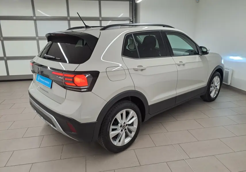 Vue 3/4 arrière droite d'un Volkswagen T-Cross 2024 gris Ascot avec feux arrière allumés en intérieur.