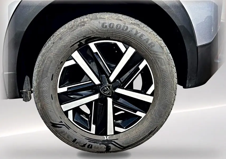 Gros plan sur la roue avant droite du Peugeot 2008 gris, mettant en valeur la jante noire et argentée au design moderne.