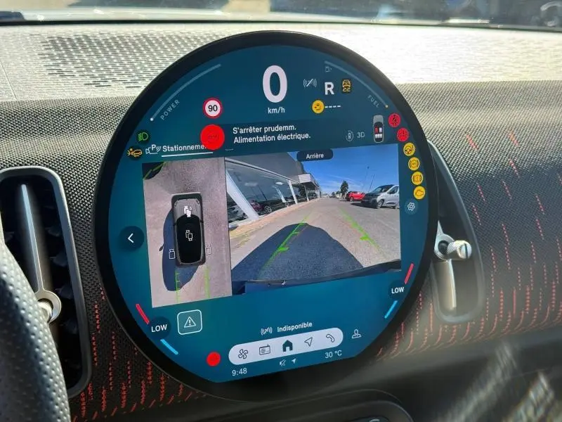 Affichage numérique circulaire du tableau de bord du MINI Countryman argenté, montrant la caméra de recul et les alertes de conduite.
