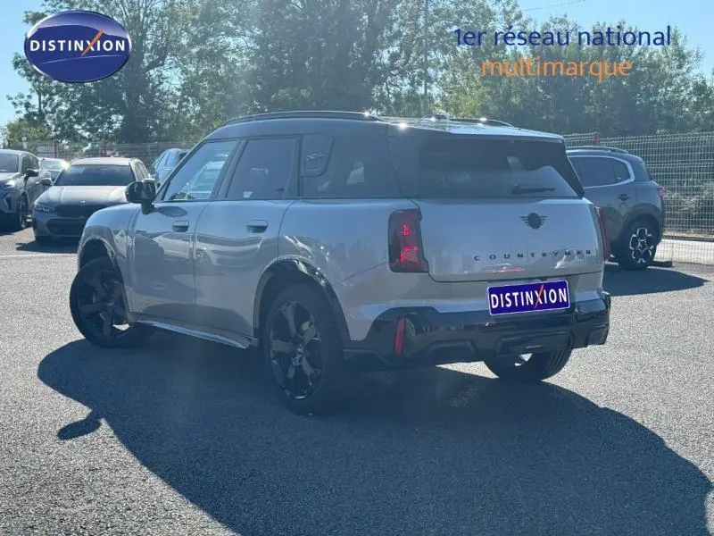 Vue 3/4 arrière droite d'un MINI Countryman argenté avec toit noir et jantes noires, stationné en extérieur.
