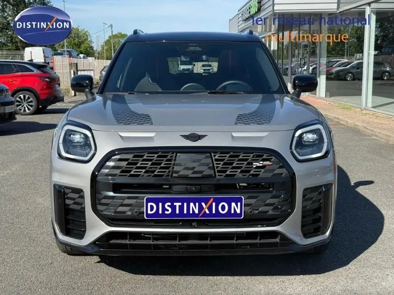 Vue frontale d'un MINI Countryman argenté avec calandre noire et bandes décoratives sur le capot.