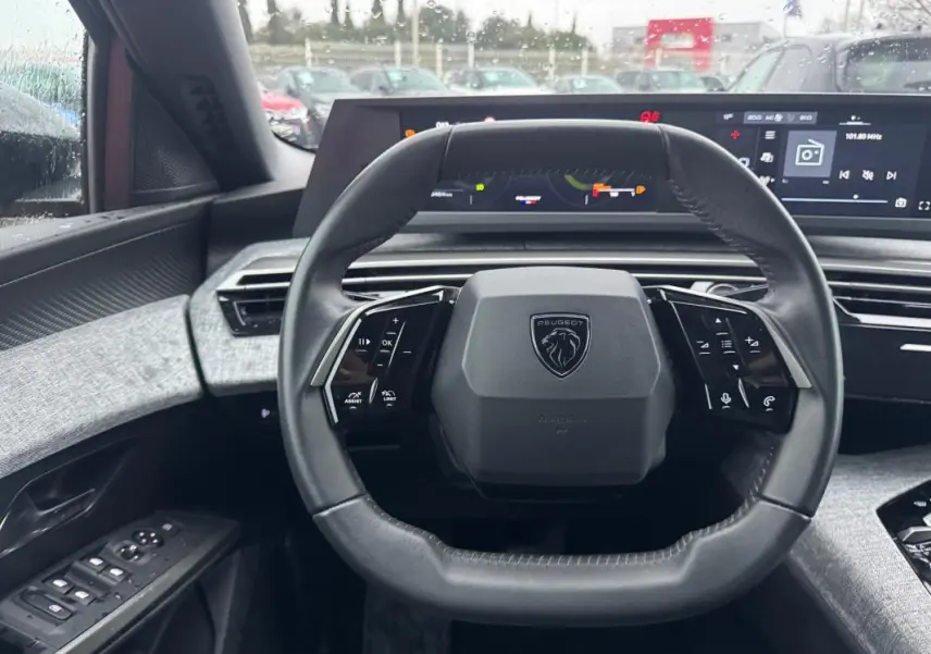 Vue intérieure centrée sur le volant cuir noir du Peugeot 3008 Hybrid 145 e-DCS6 Allure avec cockpit numérique en arrière-plan.